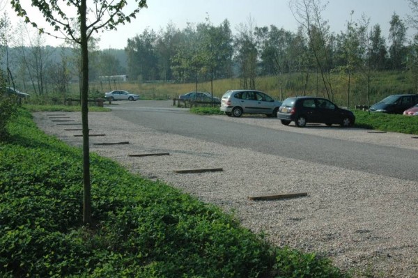 Stationnement avec allée centrale en enrobé, places en gravillons et séparateurs en bois, avec espaces plantés tout autour. Un vocabulaire d’aménagement qui s’adapte bien aux sites naturels.