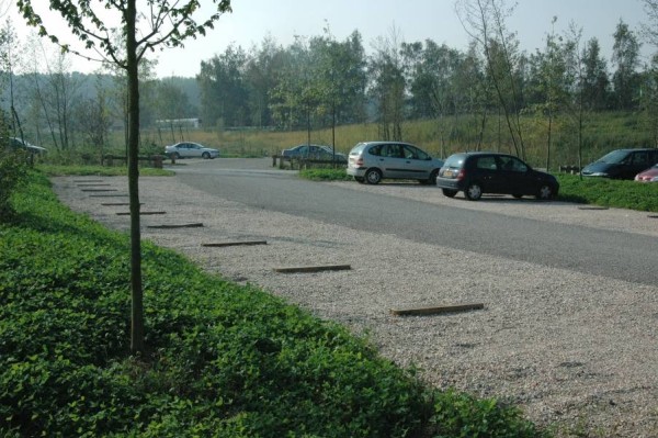 Stationnement avec allée centrale en enrobé, places en gravillons et séparateurs en bois, avec espaces plantés tout autour. Un vocabulaire d’aménagement qui s’adapte bien aux sites naturels.